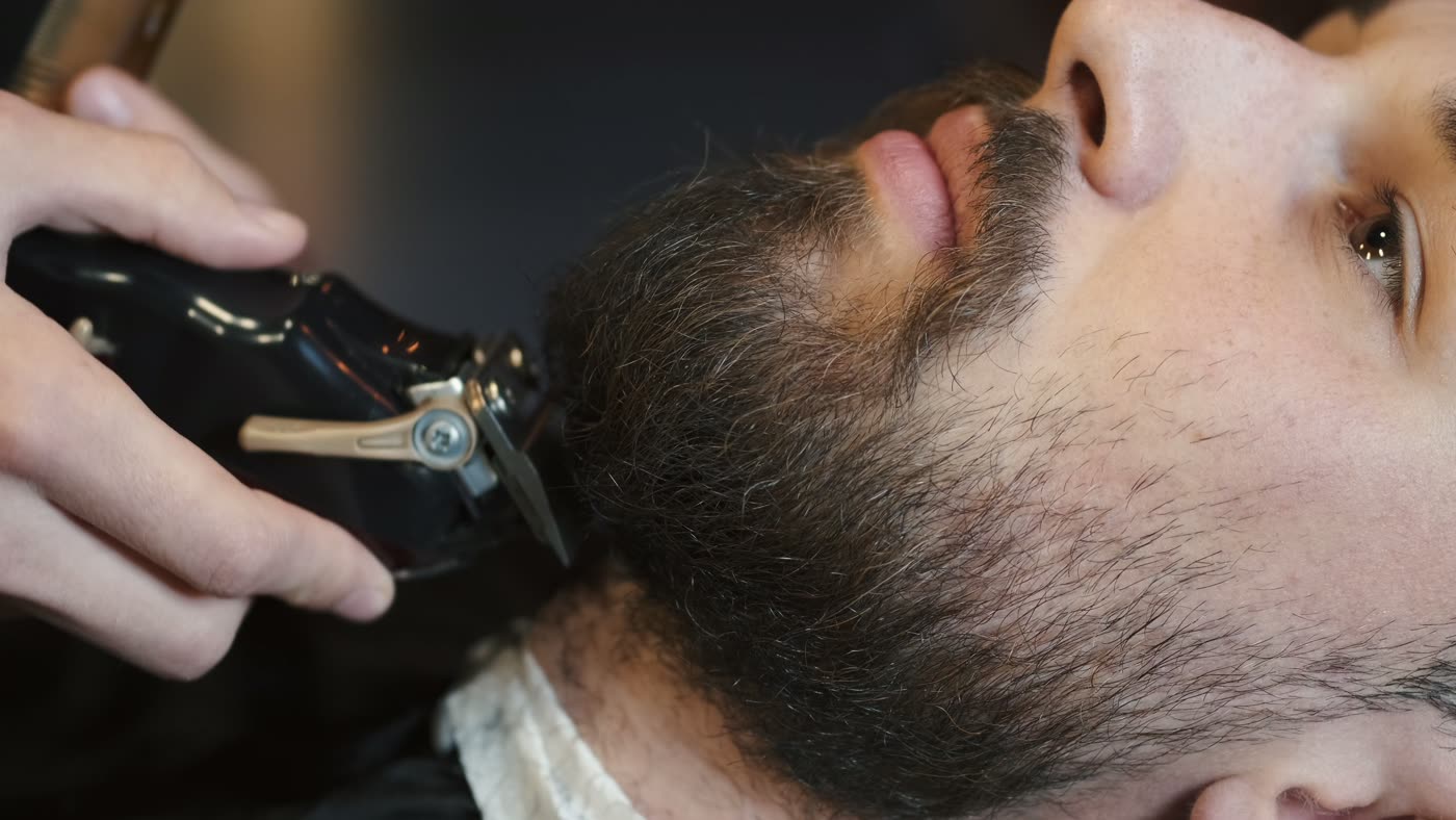 Cliente sentado na cadeira de uma barbearia moderna
